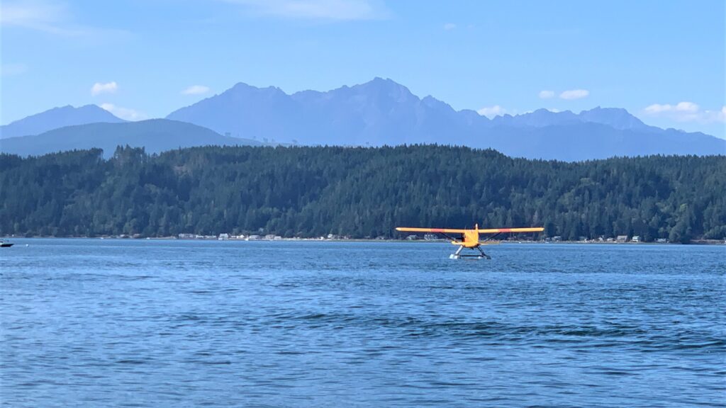 Photo of floatplane landing in Hood Canal; mountains in the background