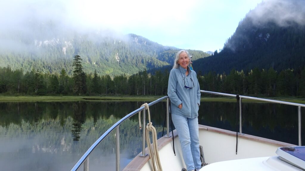 Photo of Karen on bow of boat, with fog lifting in Alison Sound