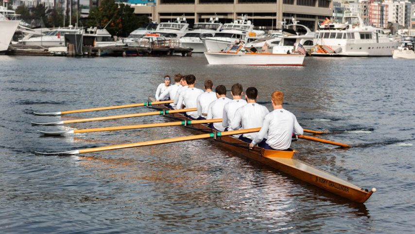 Closeup of the beautiful wood Husky Challenger rowing shell with team members wearing the iconic white shirts