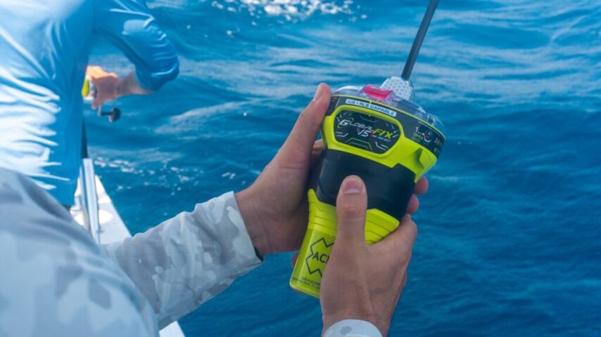 Photo of a person holding an EPIRB device while aboard a small boat