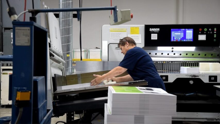 Worker at Walsworth stacking printed signatures