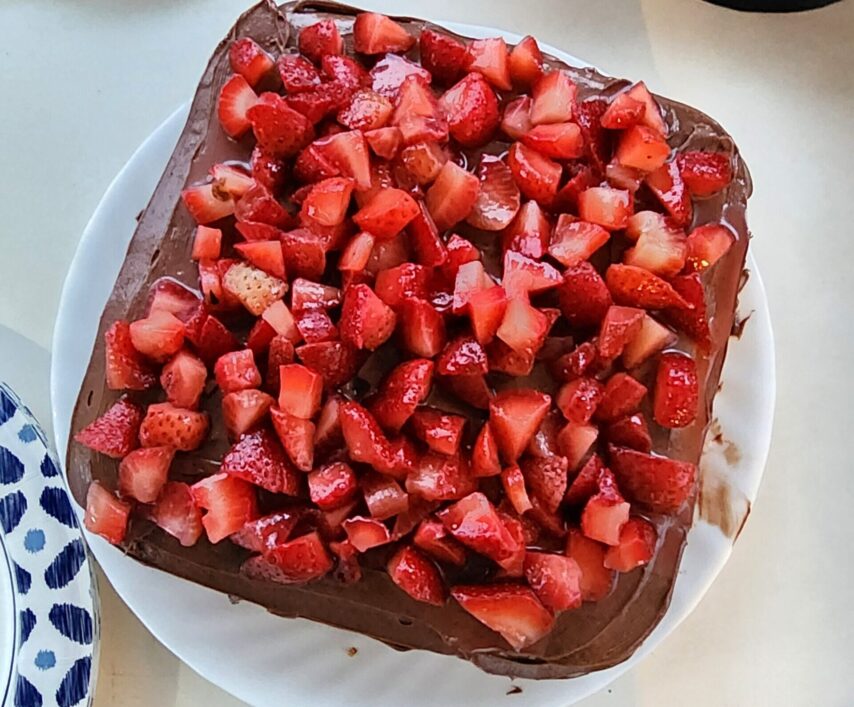 A chocolate cake covered in cut up strawberries