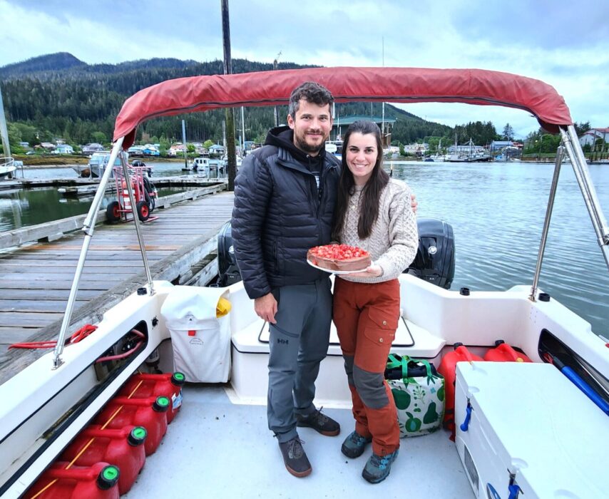 Kyle and Ashley on the stern of a flotilla boat with chocolate/strawberry cake in hand
