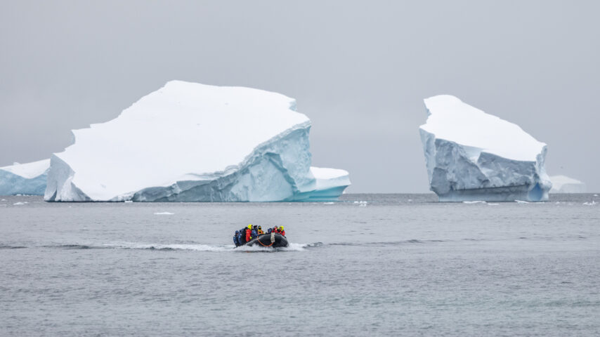 Skiff with tourists motoring among the huge icebergs