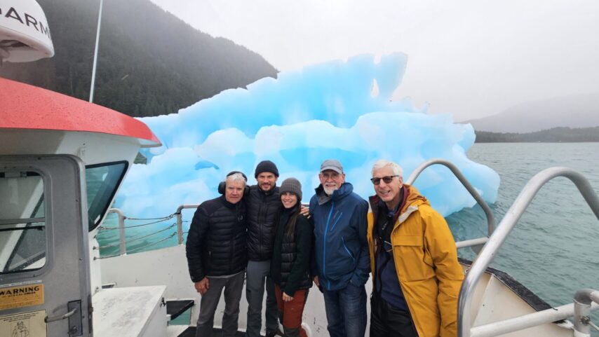 Flotilla group standing on tour boat in front of a large ice berg on the way to Le Conte Glacier