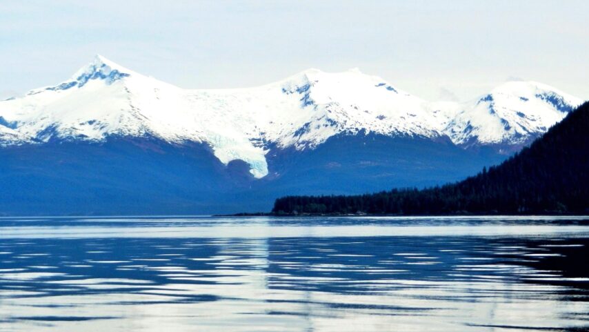 Photo of Holkum Bay with snow peaked mountains and hanging glacier in background