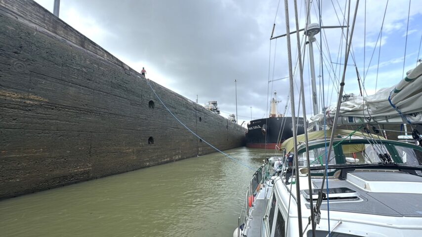 Photo of lock line going to s/v One Ocean with large ship behind them in the locks.