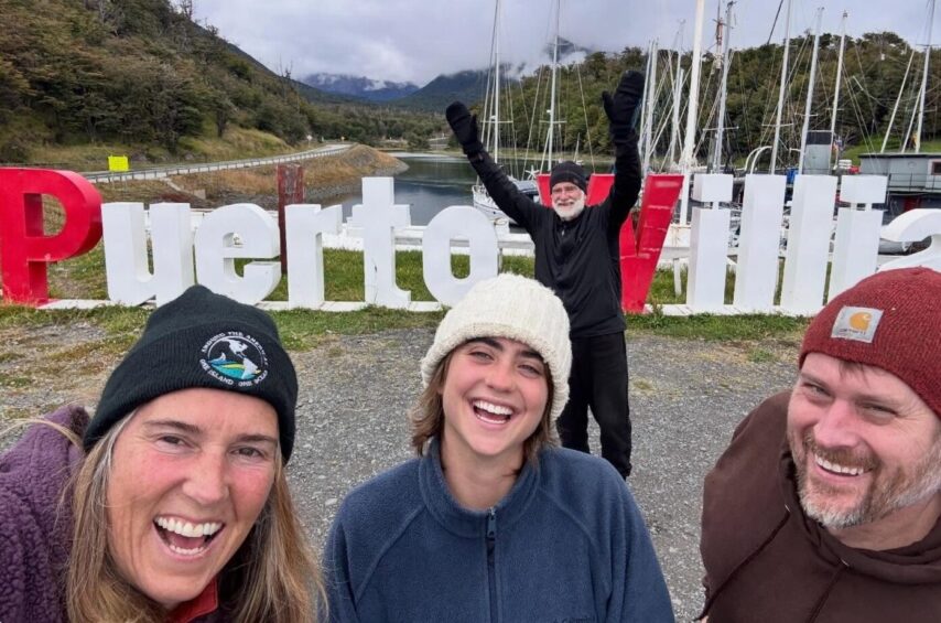 Photo of crew in front of Puerto Williams signage