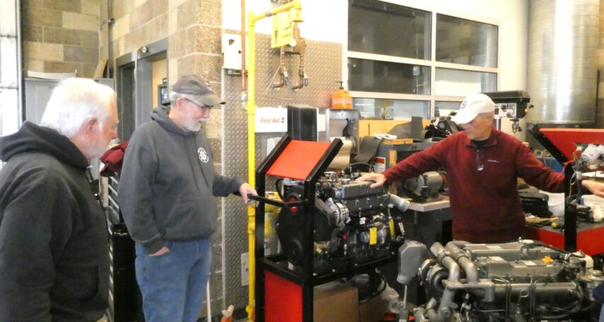 The three volunteers in discussions around marine engines